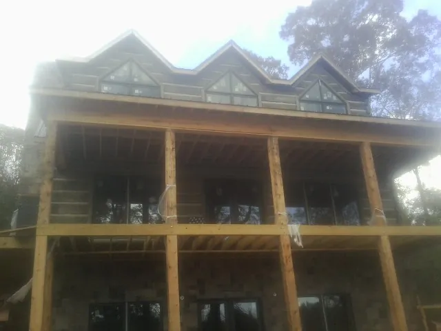 Dormers and porch framing on a large log home under construction — Roof Coating work by our crew in Vicksburg