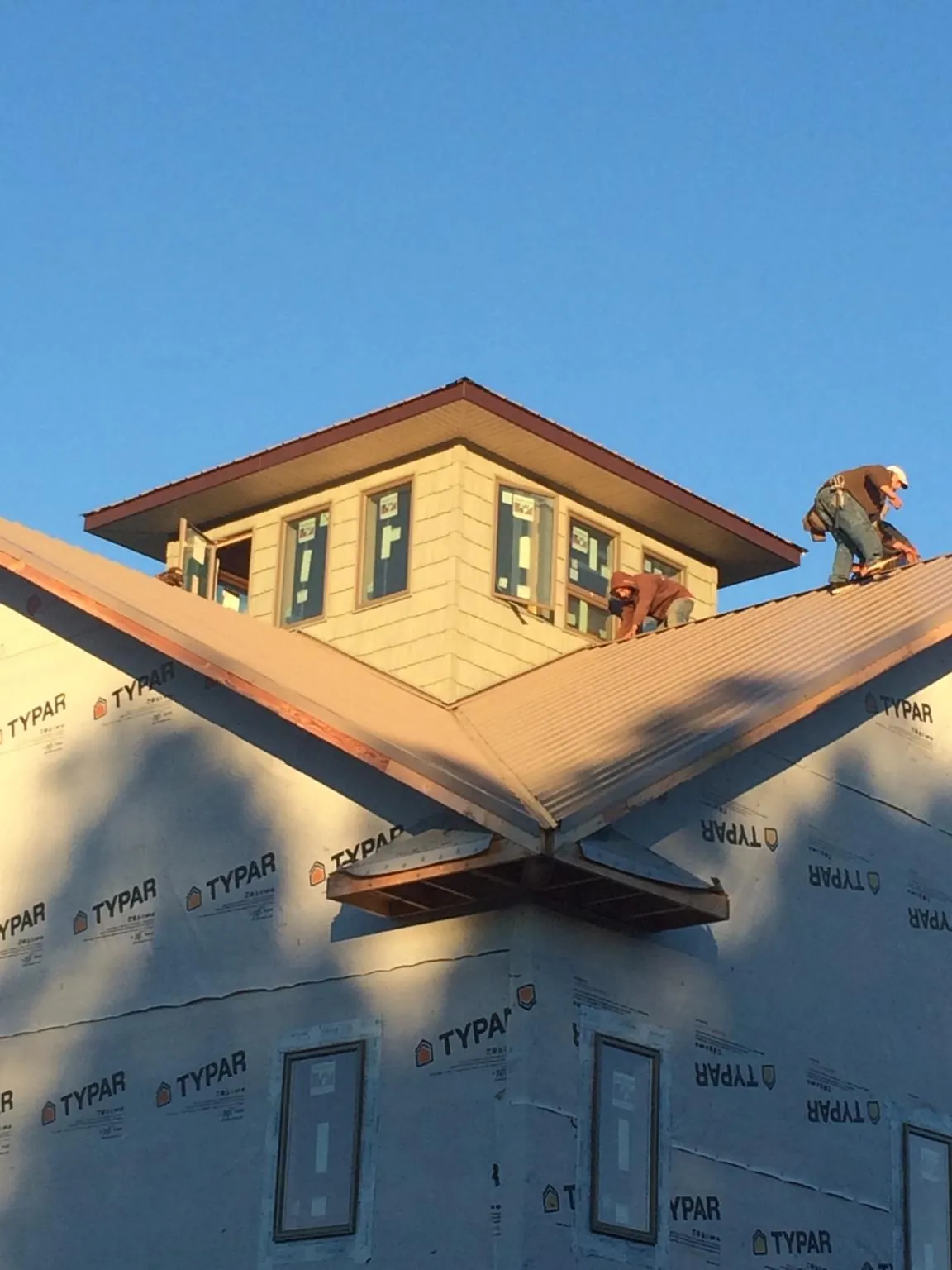 Roofers working around a rooftop cupola on a new metal roof at sunset — Roof Waterproofing in Vicksburg by Roofing Brothers